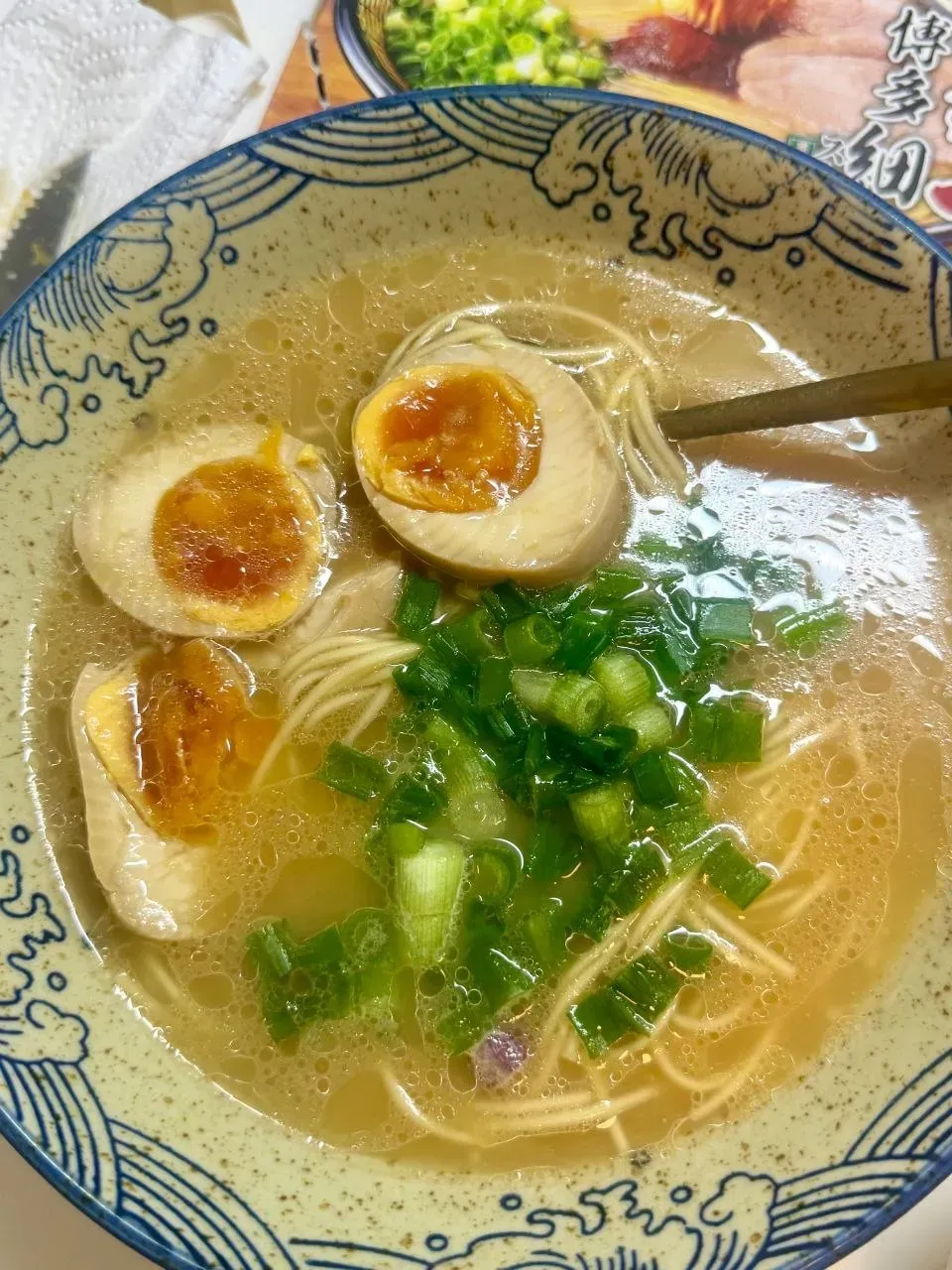 A bowl of ramen topped with halved marinated eggs and chopped green onions.