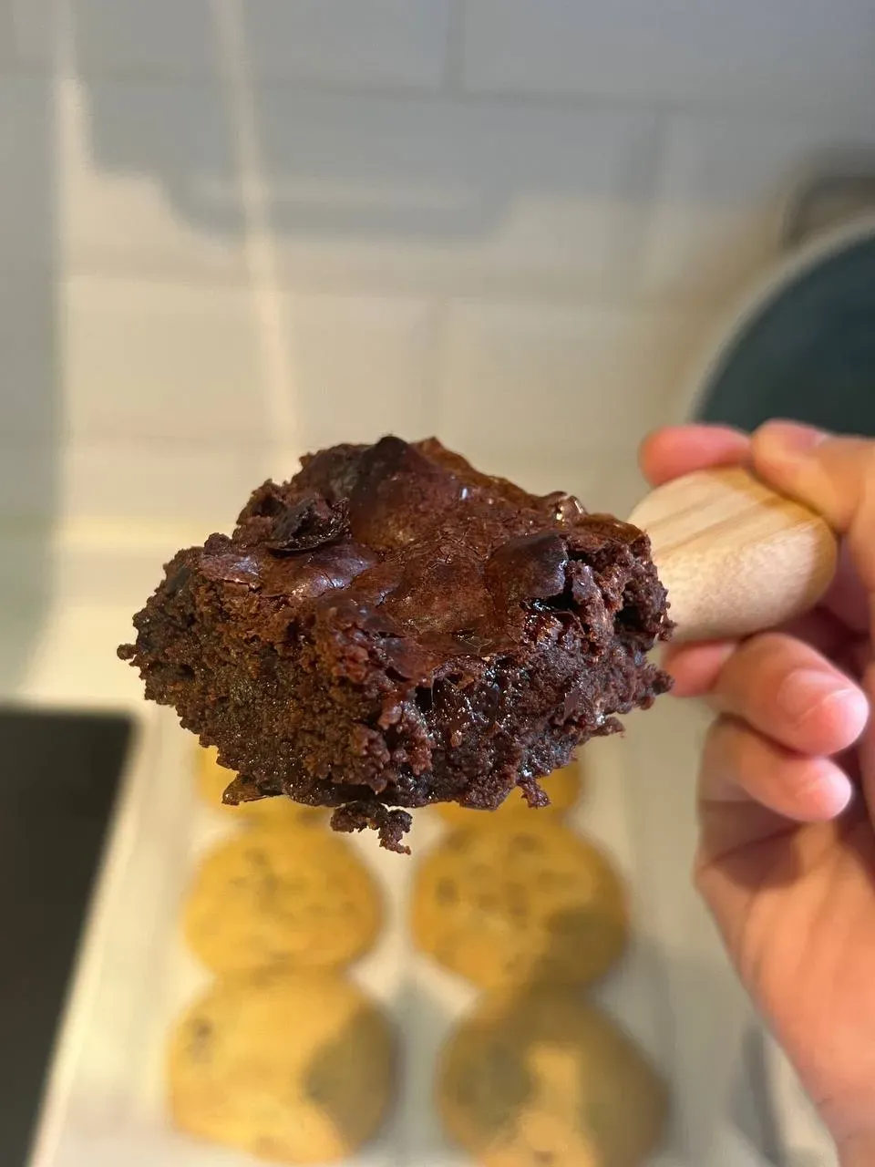 A chocolate brownie held on a wooden spatula.